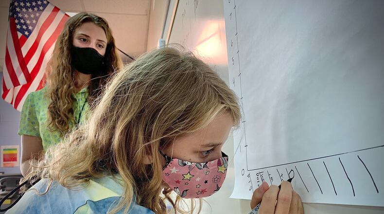 Virginia Stevenson Elementary School third-grader Temperance Breehe does work on the board under the watchful eyes of teacher Tessler Baird on the first day of school, Tuesday, Sept. 7, 2021. MARSHALL GORBY\STAFF