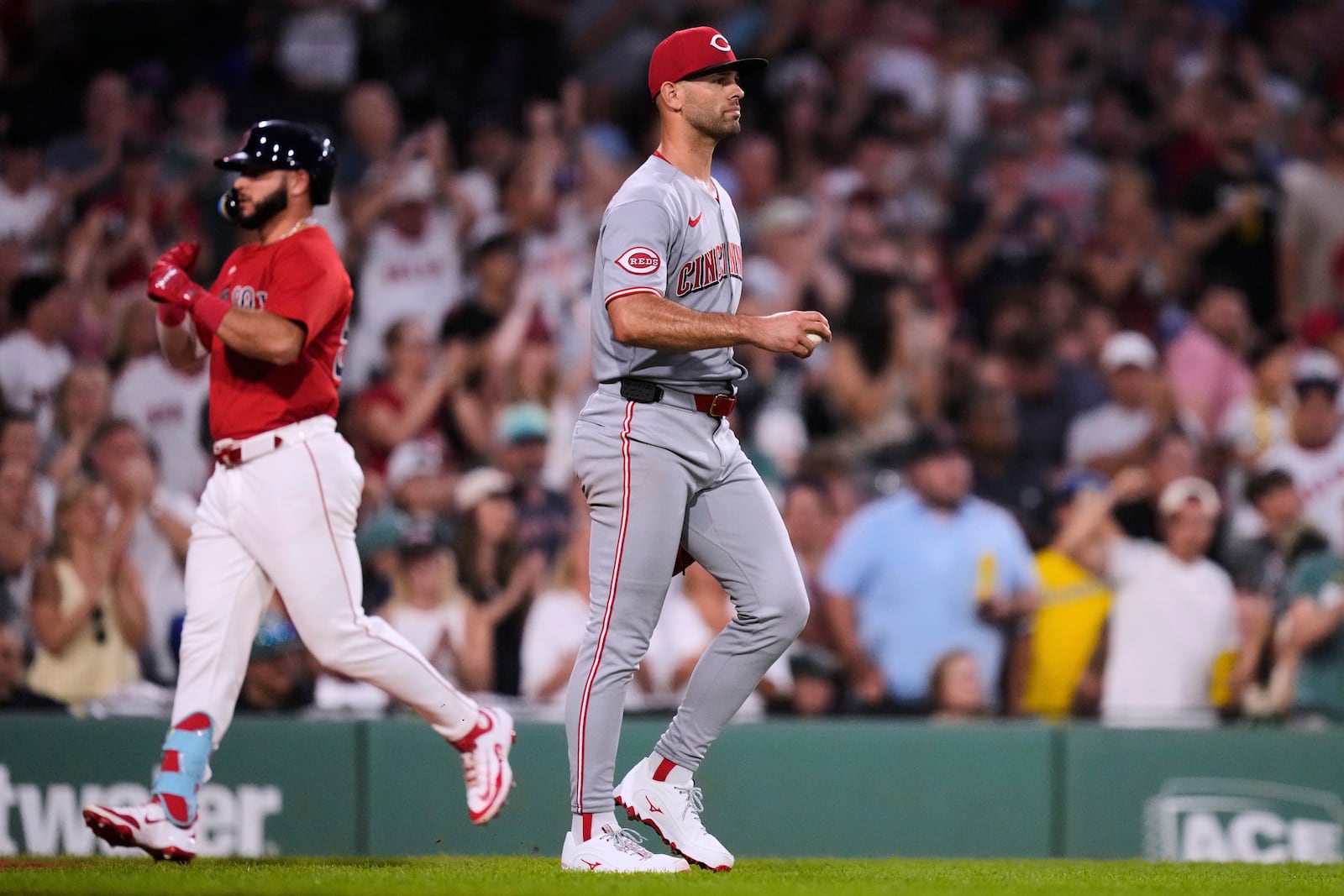 Cincinnati Reds pitcher Nick Martinez walks back to the mound with a fresh baseball as Boston Red Sox's Wilyer Abreu, left, rounds the bases on his two-run home run during the sixth inning of a baseball game at Fenway Park, Wednesday, July 2, 2025, in Boston. (AP Photo/Charles Krupa)