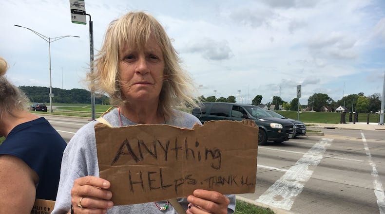 Abigail O’Neil, holding a sign at the intersection of Stewart Street and Patterson Boulevard, pulled up her sleeves to show she has no needle marks. “I’m no drug addict. You’re not going to find one needle mark except where a doctor took blood,” she said.