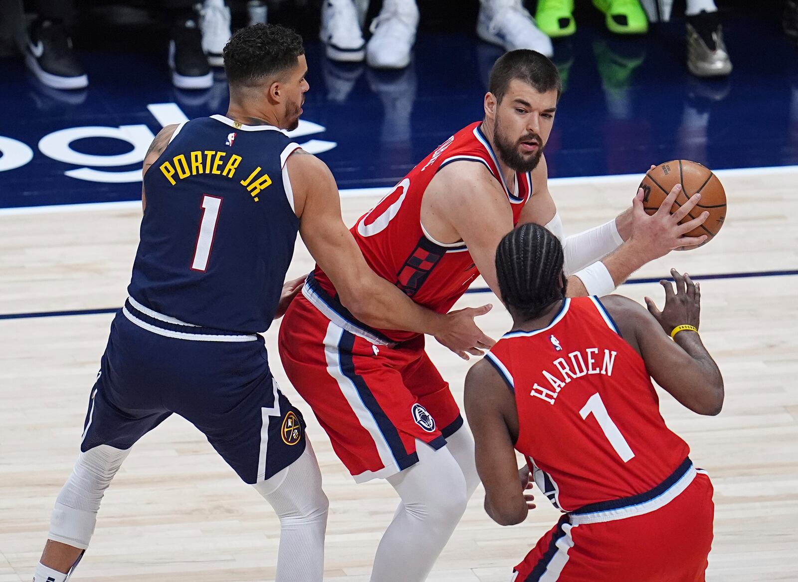Los Angeles Clippers center Ivica Zubac, top right, looks to pass the ball to guard James Harden, bottom right, as Denver Nuggets forward Michael Porter Jr., left, defends in the first half of Game 2 of a first-round NBA playoff series Monday, April 21, 2025, in Denver. (AP Photo/David Zalubowski)
