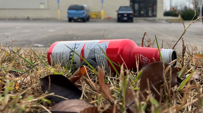 An empty beer bottle in a grassy area outside of a Dollar General's parking lot in Dayton. CORNELIUS FROLIK / STAFF
