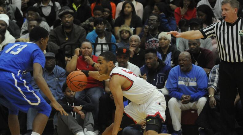 Trotwood-Madison’s Amir Foster (with ball) is checked by Dunbar’s Joseph Scates during the Rams’ 98-89 win on Feb. 4. Trotwood is a No. 1 seed and Dunbar No. 2 in the D-II sectional. MARC PENDLETON / STAFF