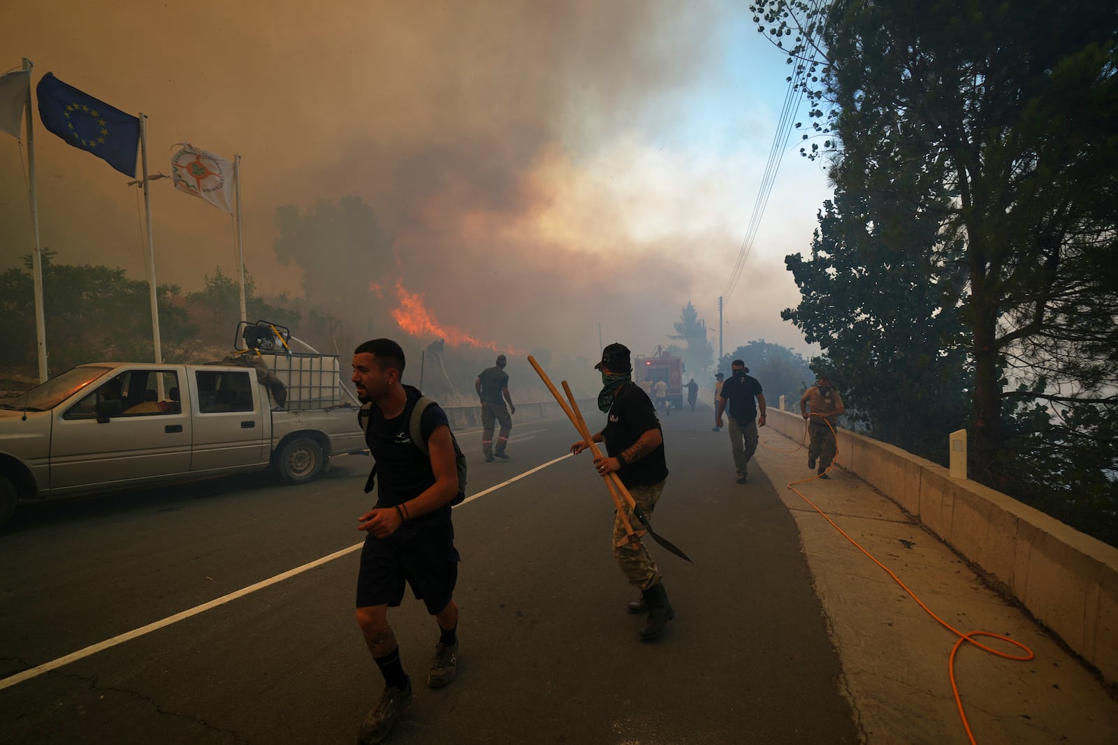Residents try to extinguish the blazes in Omodos village, Cyprus, during a massive wildfire on the southern side of the east Mediterranean island nation's Troodos mountain range, Thursday, July 24, 2025. (AP Photo/Petros Karadjias)