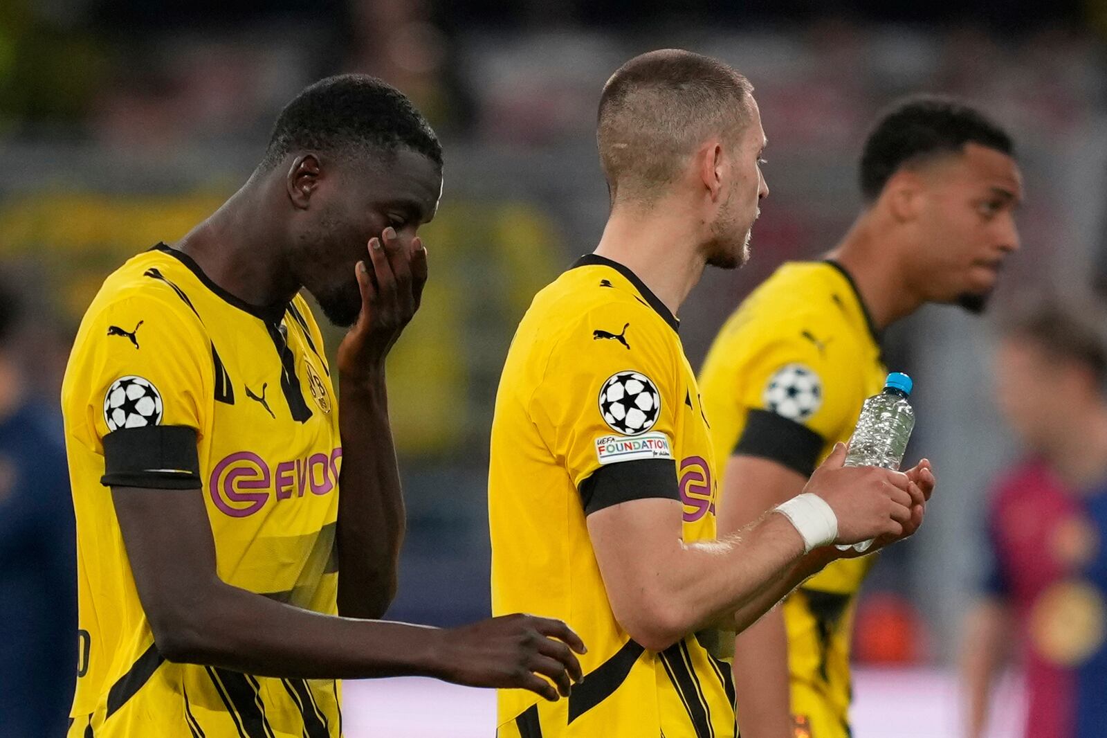Dortmund's Serhou Guirassy, left, leaves the field with teammates after the Champions League quarterfinals second leg soccer match between Borussia Dortmund and Barcelona, at the Signa-Iduna Park in Dortmund, Germany, Tuesday, April 15, 2025. (AP Photo/Martin Meissner)
