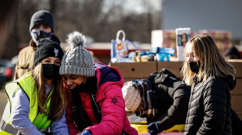 Volunteers from left, Parker Karban, Lauren Belyeu and Averie Back dig out food items to load into cars at the Dixie Drive-In. The Christmas food giveaway was run by the With God's Grace charity group, along with the Levin Family Foundation. JIM NOELKER/STAFF