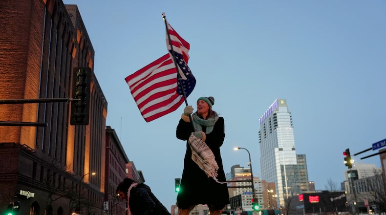 Teresa Hurst waves an upside-down American flag on top of a car during a rally against federal immigration enforcement on Friday, Jan. 23, 2026, in Minneapolis. (AP Photo/Angelina Katsanis)