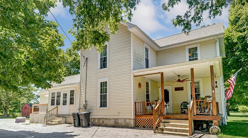 The house has a covered front porch with railings and a ceiling fan. It has updated vinyl siding and an unfinished basement.