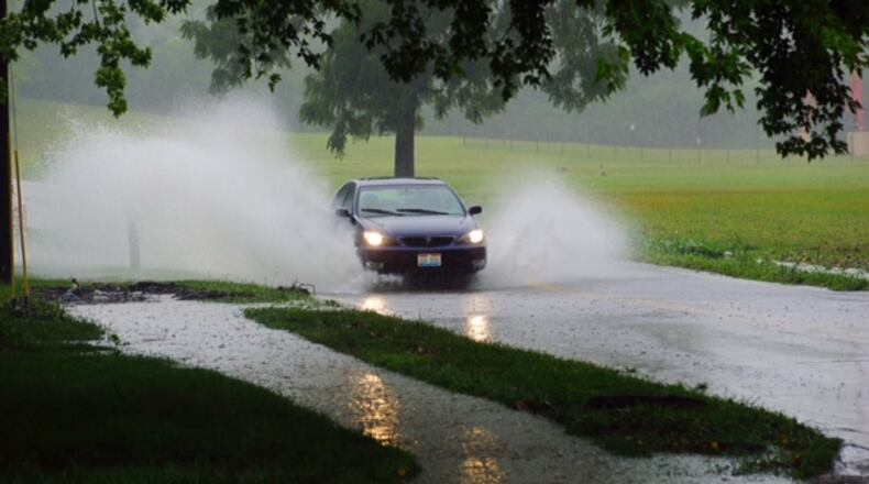 A car travels through standing water Sunday, Aug. 14, 2016, on Rahn Road in Washington Twp., Montgomery County. (Jordyn Huffman/Staff)