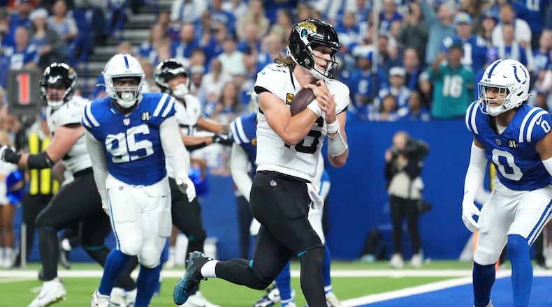 Jacksonville Jaguars quarterback Trevor Lawrence scores past Indianapolis Colts defensive tackle Adetomiwa Adebawore (95) and safety Camryn Bynum (0) during the second half of an NFL football game Sunday, Dec. 28, 2025, in Indianapolis. (AP Photo/AJ Mast)