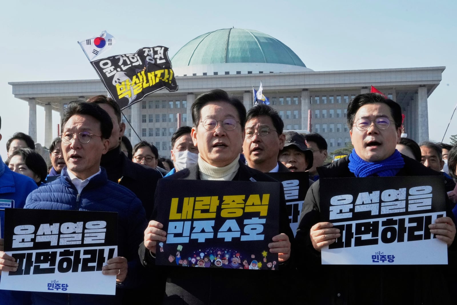 FILE - South Korea's main opposition Democratic Party leader Lee Jae-myung, center, and his party members shout slogans during a rally calling for impeached South Korean President Yoon Suk Yeol's dismissal at the National Assembly in Seoul, South Korea, March 19, 2025. The letters read "Dismiss Yoon Suk Yeol." (AP Photo/Ahn Young-joon, File)