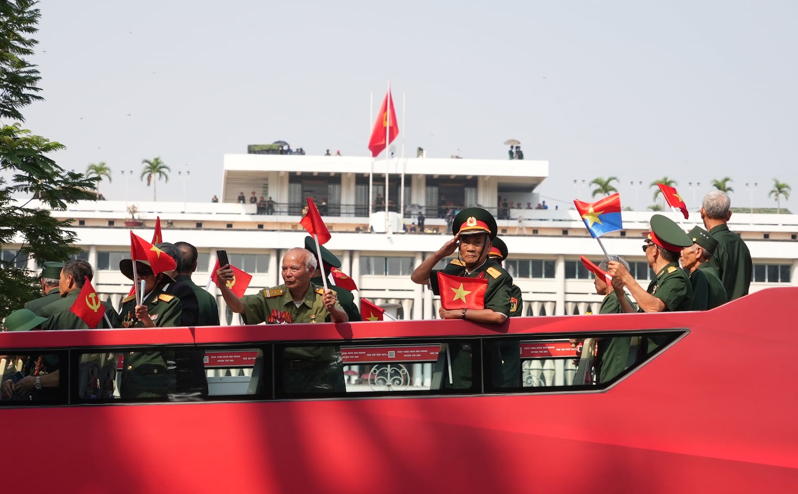 Vietnam War veterans on an open bus pass the Independence Palace during a parade to commemorate the 50th anniversary of the end of the Vietnam War in Ho Chi Minh City Wednesday, April 30, 2025. (AP Photo/Hau Dinh)