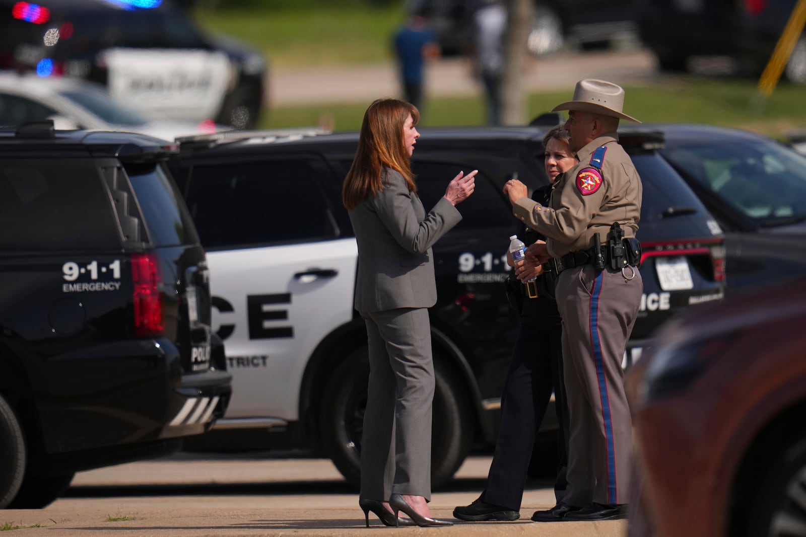 Superintendent Stephanie Elizalde, left center, speaks with a highway patrolman outside Wilmer-Hutchins High School after authorities reported the campus had been secured following reports of a shooting, in Dallas, Tx., Tuesday, April 15, 2025. (AP Photo/Julio Cortez)