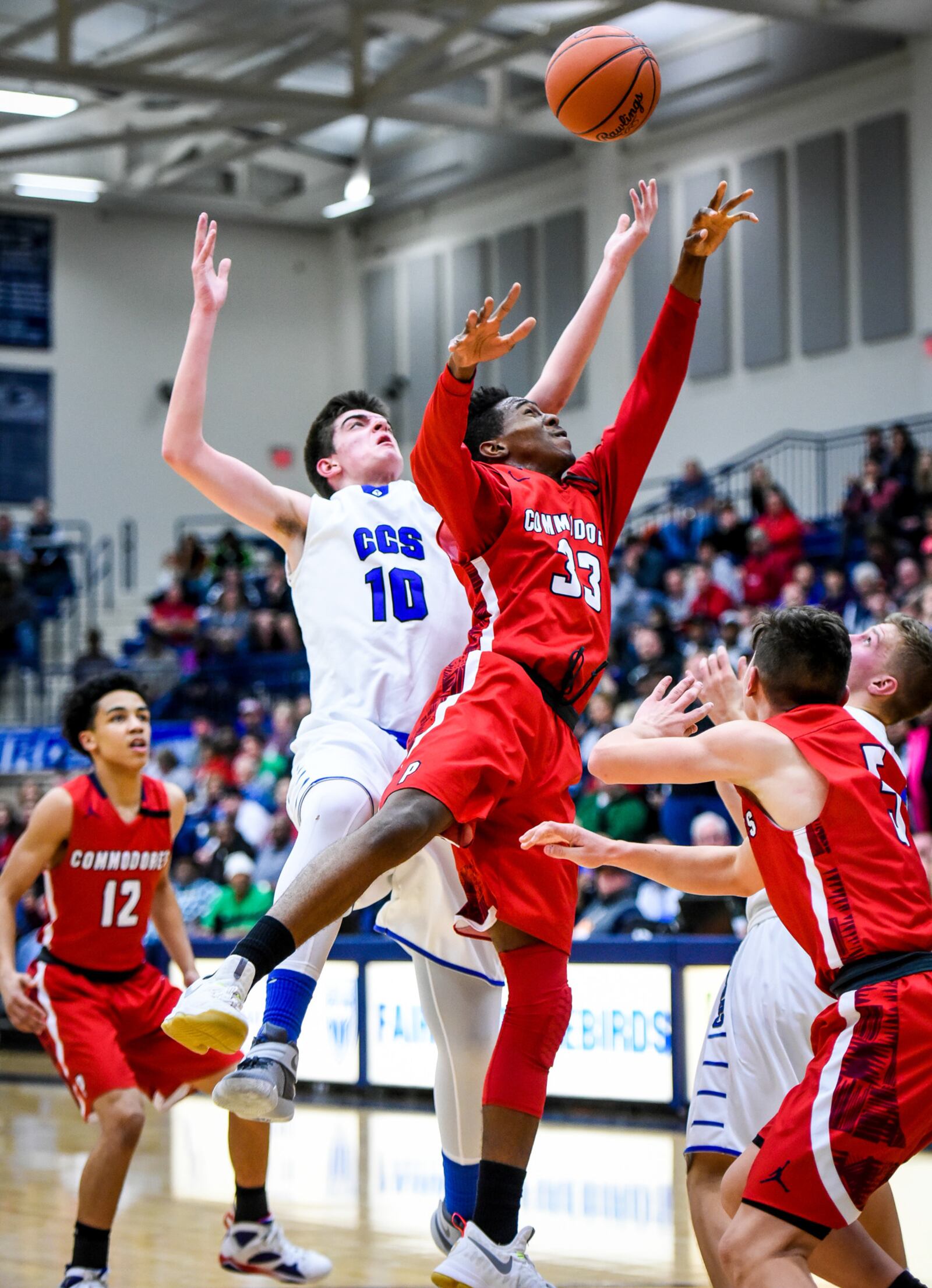 Cincinnati Christian’s Nick Hesselgesser (10) and Lima Perry’s LaMonte’ Nichols (33) leap for the ball Friday night during a Division IV regional final at Fairmont’s Trent Arena. NICK GRAHAM/STAFF