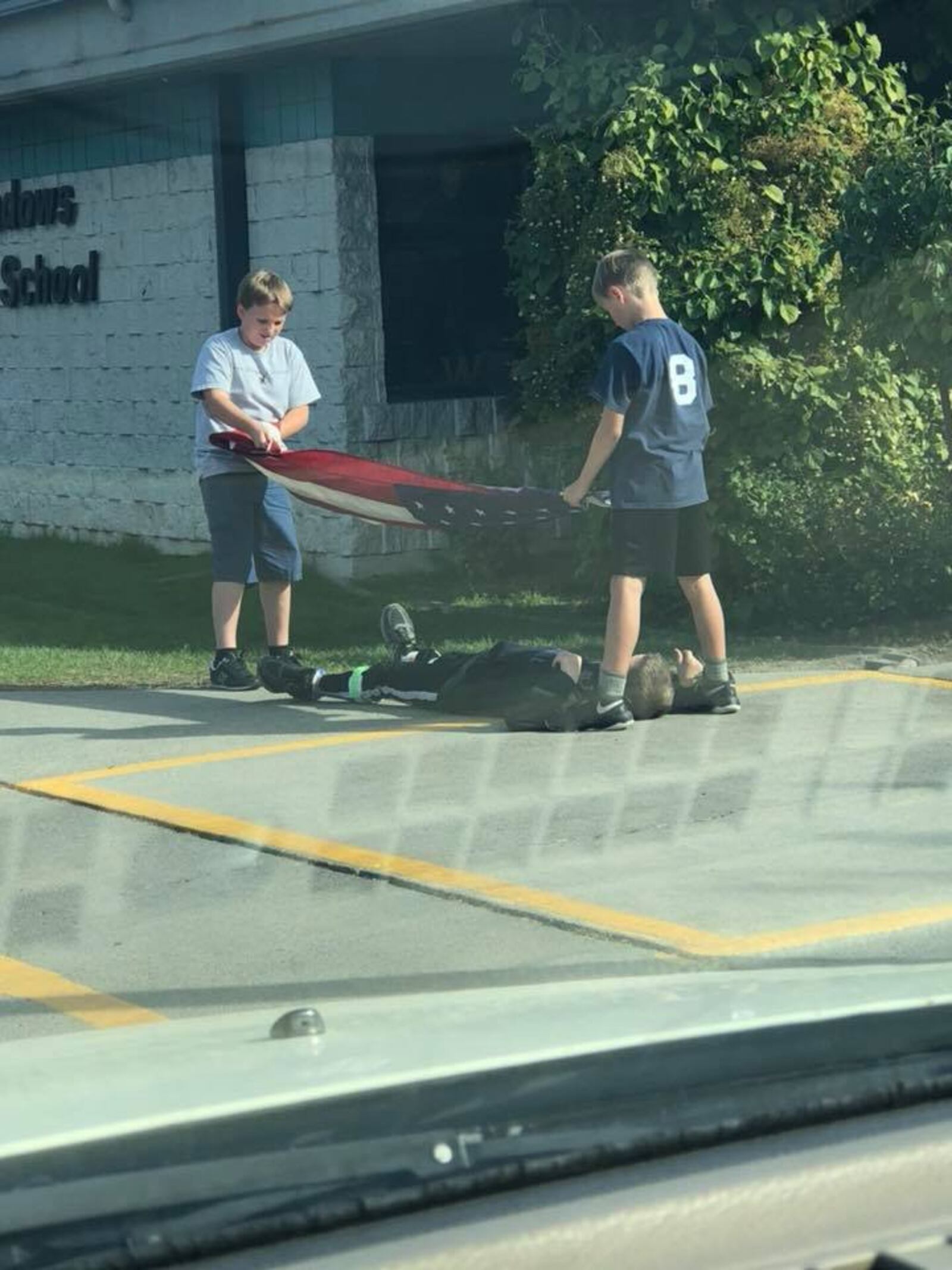 Jack LeBreck — a fifth grader at Hayden Meadows Elementary School in Hayden, Idaho — lays on the ground to protect the American flag in a photo taken Wednesday.