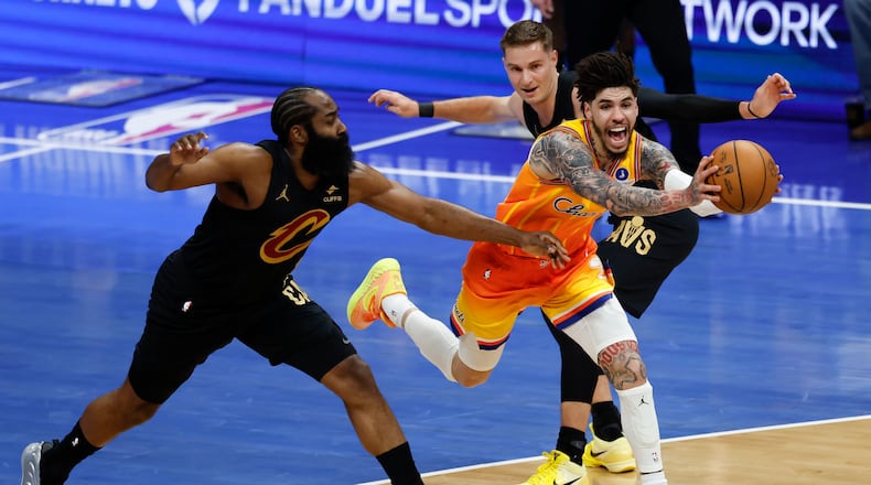 Charlotte Hornets guard LaMelo Ball, front right, drives between Cleveland Cavaliers guards James Harden, left, and Sam Merrill, back right, during the first half of an NBA basketball game in Charlotte, N.C., Friday, Feb. 20, 2026. (AP Photo/Nell Redmond)
