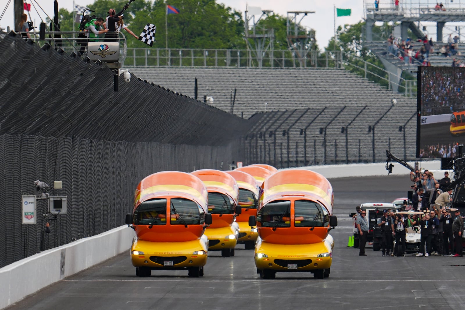 The Oscar Mayer Wienermobiles take the checkered flag after completing the Wienie 500 following the practice session for the Indianapolis 500 auto race at Indianapolis Motor Speedway in Indianapolis, Friday, May 23, 2025. (AP Photo/Michael Conroy)
