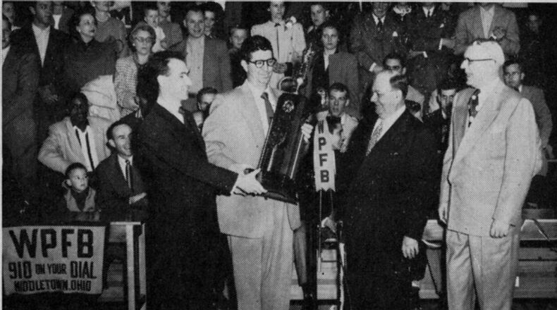 Longtime Journal Sports Editor Jerry Nardiello hands a state championship trophy to Coach Paul Walker as Wade E. Miller watches.
