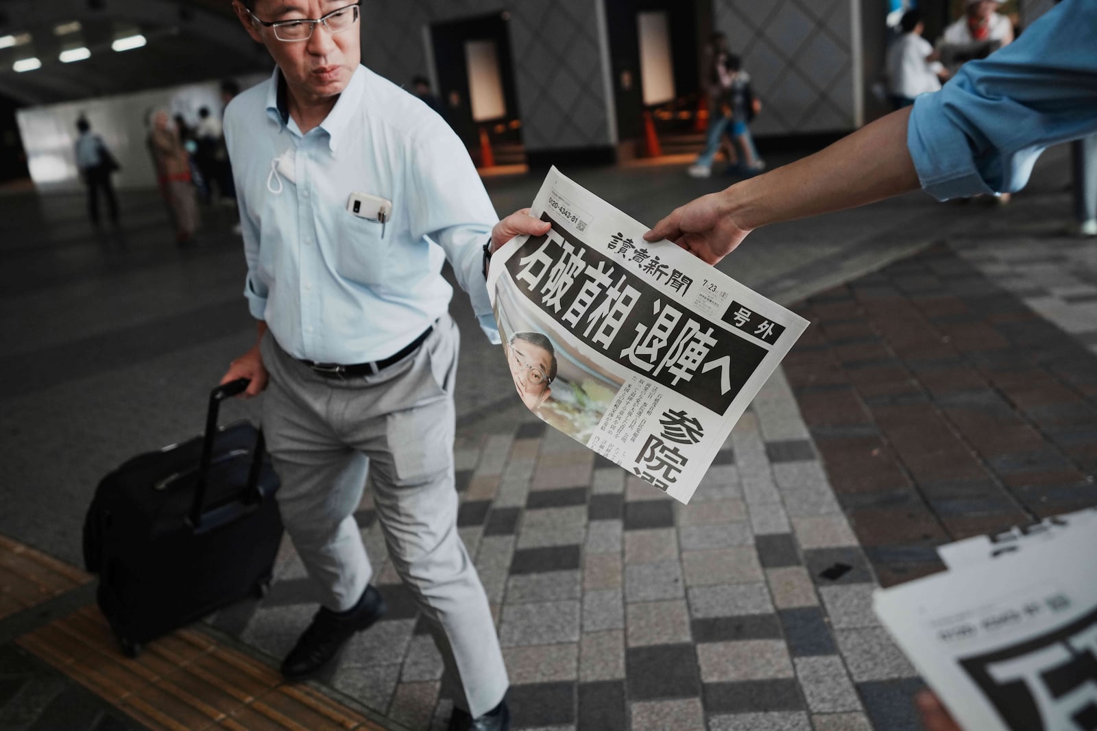 A person receives an extra edition of the Yomiuri Shimbun newspaper, with headline reading "Prime Minister Ishiba towards resignation," in Tokyo, Wednesday, July 23, 2025. (AP Photo/Eugene Hoshiko)