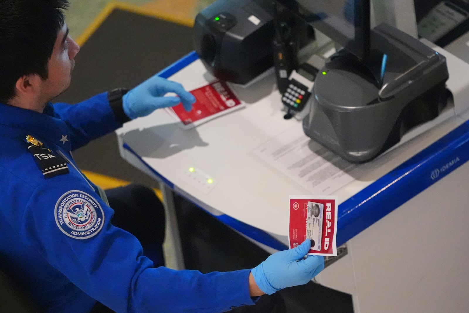 A TSA agent hands off a non-Real ID for a traveler passing through security at Love Field airport in Dallas, Wednesday, May 7, 2025. (AP Photo/LM Otero)