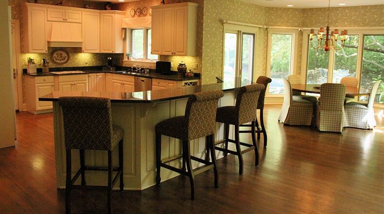 A semi-circular breakfast bar tiered above the center island creates a separation between great room and kitchen.Styling features in the kitchen include wood flooring, Hawaiian granite counters, oversized cabinets with upper moldings and recessed ceiling lights.