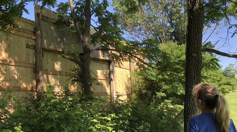 Pam Freson looks toward a fence towering along the property line with neighbors she and her husband are at odds with in rural Warren County. Next door, Rachel and Scott Walker operate a concrete business on their property. STAFF/LAWRENCE BUDD