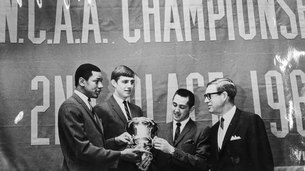 Dayton Flyers basketball players (left to right) Glinder Torain, Dan Obrovac, and Gene Klaus admire a trophy presented to them by Dayton Area Chamber of Commerce President Bob Margolis on April 7, 1967. Dayton Daily News photo by Al Wilson, courtesy of Wright State University archive.
