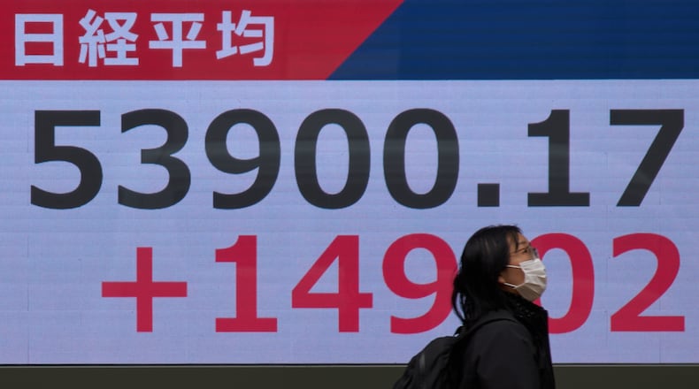 A person walks near a stock price monitor showing Nikkei index at a security company Tuesday, March 17, 2026, in Tokyo. (AP Photo/Eugene Hoshiko)