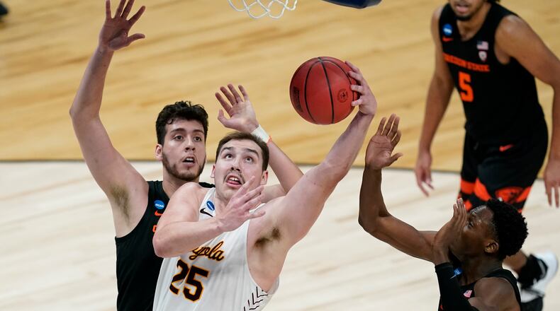 Loyola Chicago center Cameron Krutwig (25) drives to the basket between Oregon State center Roman Silva, left, and forward Warith Alatishe, right, during the second half of a Sweet 16 game in the NCAA men's college basketball tournament at Bankers Life Fieldhouse, Saturday, March 27, 2021, in Indianapolis. (AP Photo/Darron Cummings)