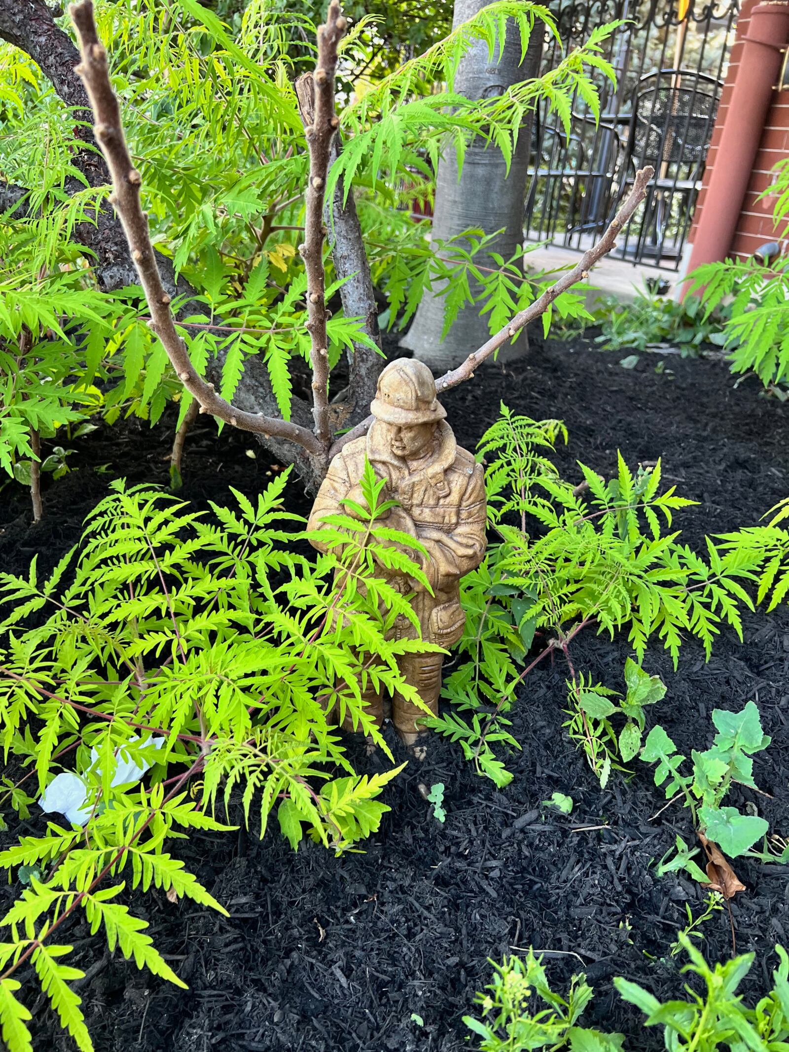 A statue of a firefighter sits outside surrounded by plants as you enter the door of Jimmie's Ladder 11