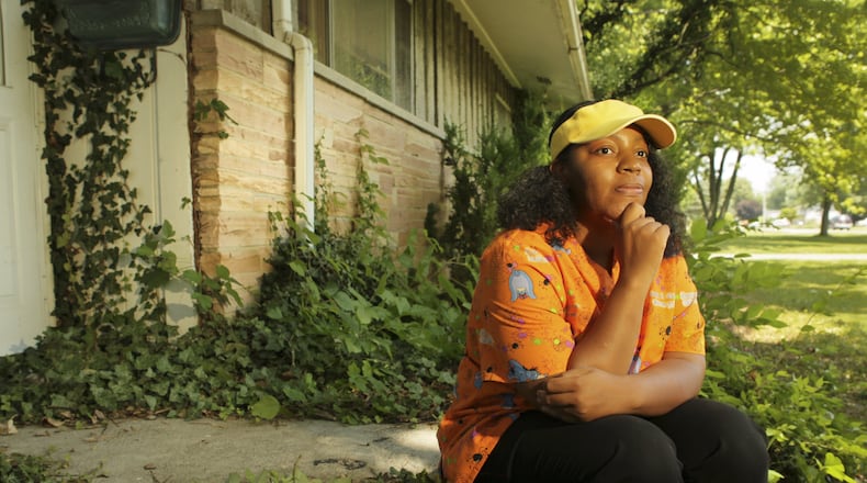 Erica Grissom sits on her front steps at 3691 Denlinger Road in Trotwood. Grissom's house was foreclosed on by a bank and she was forced to move. Years later, and $15,000 delinquent in property taxes, Grissom found out the house is still in her name. She is currently living in the house and working with Miami Valley Fair Housing to secure grants that will cover the back taxes and pay off the mortgage.