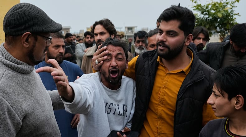 People comfort a man, center, mourning over the death of his relative, close to the site of a bomb explosion at a Shiite mosque, in Islamabad, Pakistan, Friday, Feb. 6, 2026. (AP Photo/Anjum Naveed)