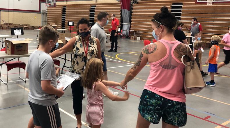 Danielle Romine, K-6 curriculum director for Troy City Schools, wishes fifth-grader Brayden Clark and kindergartner Raelynn Clark a happy school year after they picked up Chromebook computers for online learning.