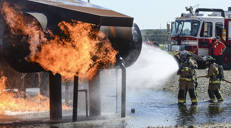 Participants in the ‘Fire Ops 101’ event at Wright-Patterson Air Force Base use hoses as they attempt to extinguish an aircraft fire during the event’s capstone exercise Sept. 28. The event allowed base and local decision-makers a chance to see the latest gear their fire departments are using and what they do on a daily basis. (U.S. Air Force photo/Wesley Farnsworth)