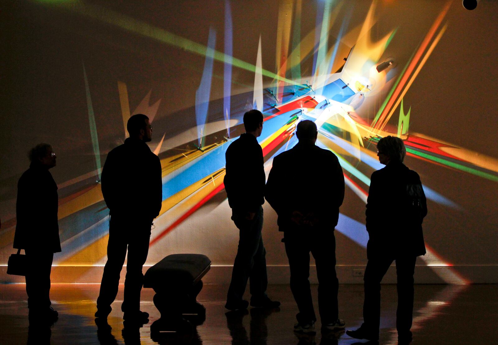 Visitors to the Dayton Art Institute view the special exhibition "Stephen Knapp: Lightpaintings". The lightpaintings, which appear to be painted on the walls, are made of light, glass and stainless steel. STAFF PHOTO BY LISA POWELL