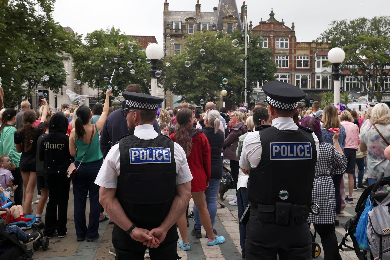 FILE - Police officers watch members of the public outside the Town Hall during a vigil to remember the victims of the stabbing attack last Monday in Southport, England, Monday, Aug. 5, 2024. (AP Photo/Darren Staples, File)