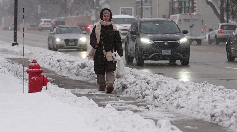 A pedestrian walks on a snow-covered sidewalk in Wheeling, Ill., Monday, Dec. 1, 2025. (AP Photo/Nam Y. Huh)