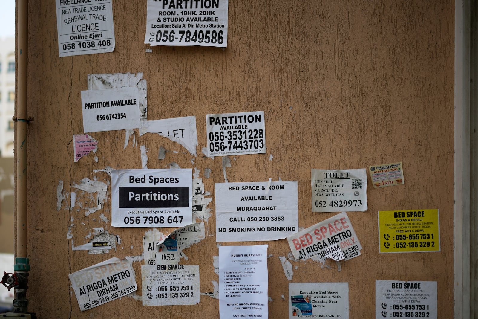 The wall of a building is plastered with advertisements for inexpensive, partitioned housing in Dubai, United Arab Emirates, Friday, July 4, 2025. (AP Photo/Altaf Qadri)