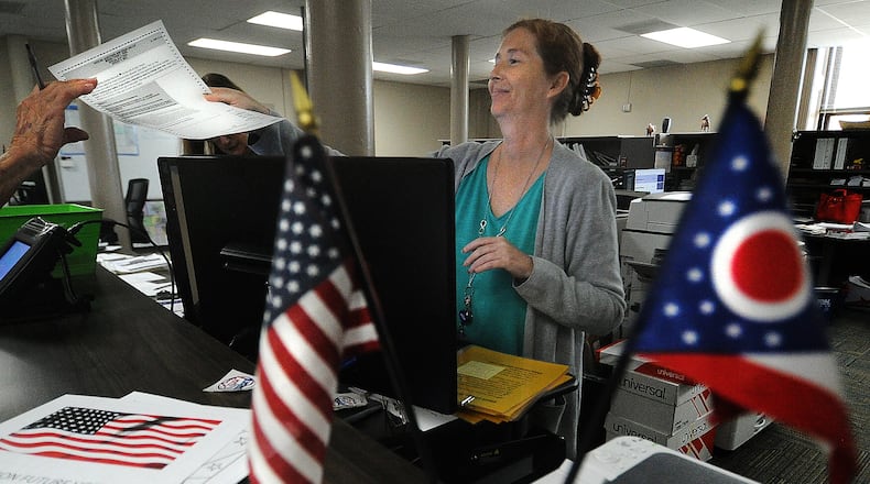 Miami County board of elections office clerk, Cheri Nevels hands a voter a ballot Friday, July 28, 2023 at the board of elections office in Troy. MARSHALL GORBY\STAFF