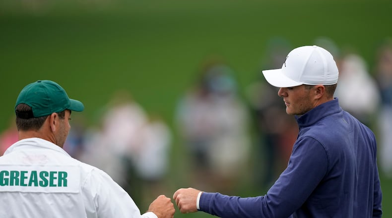 Amateur, Austin Greaser bumps fists with his caddie Andrew DiBitetto after a birdie on the second hole during the first round at the Masters golf tournament on Thursday, April 7, 2022, in Augusta, Ga. (AP Photo/David J. Phillip)