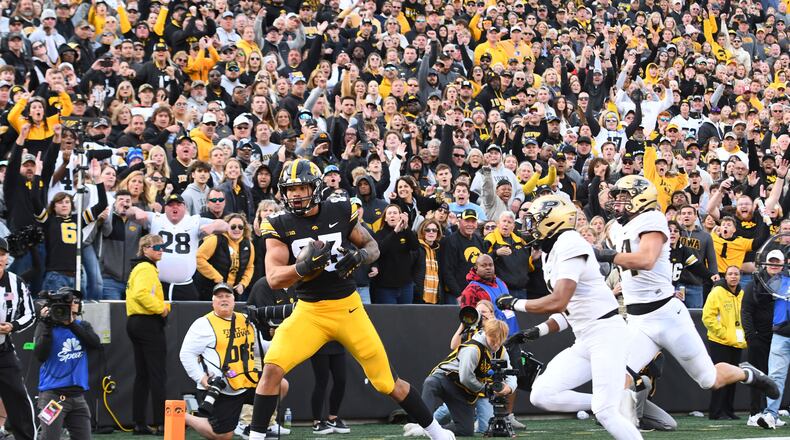 Iowa tight end Erick All (83) pulls in a pass for a touchdown under pressure from Purdue defensive back Markevious Brown (1) and linebacker Yanni Karlaftis (14) during the second half of an NCAA college football game, Saturday, Oct. 7, 2023, in Iowa City, Iowa. (AP Photo/Cliff Jette)