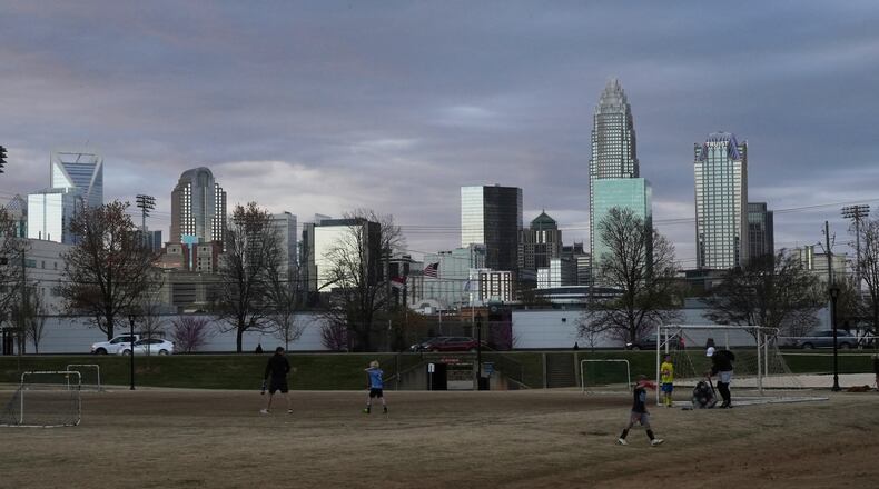 FILE - Children walk through a sports field in Independence Park under the skyline of Charlotte, N.C., on March 20, 2025. (AP Photo/Mary Conlon, File)