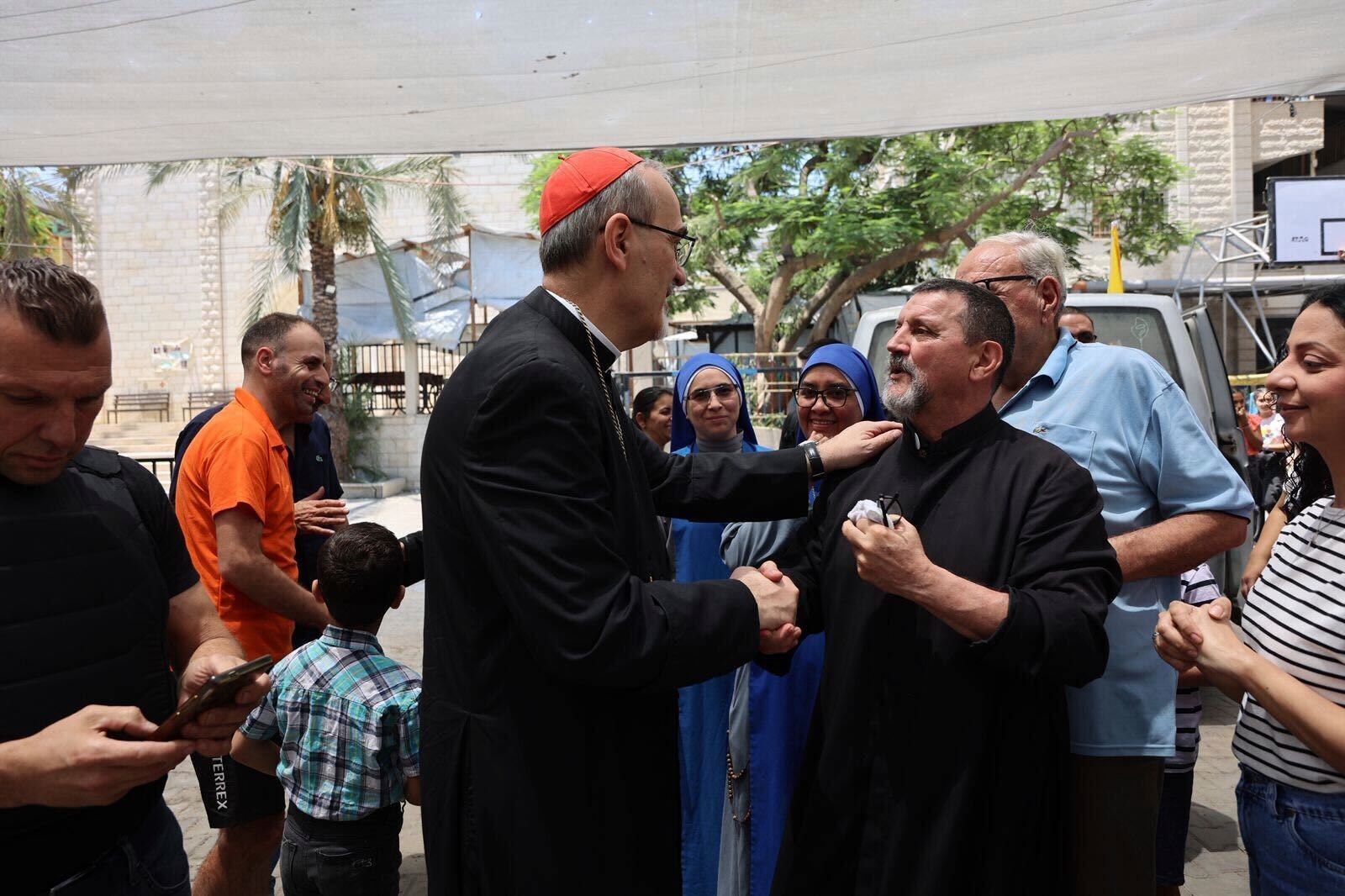 Latin Patriarch Cardinal Pierbattista Pizzaballa, center, speaks with a worshipper as part of a religious delegation to the Gaza Strip led by two patriarchs from Jerusalem visiting the Holy Family Catholic Church struck by an Israeli shell the day before in Deir al-Balah, Friday, July 18, 2025. (Latin Patriarchate of Jerusalem via AP)