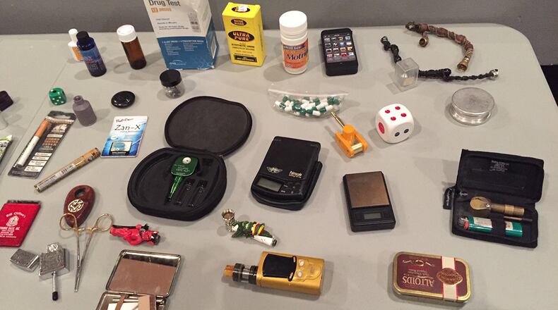 Retired investigators participating in the Operation Street Smart presentation May 21 at the Base Theater show what they have discovered and experienced through their careers, including items that can be surprising and “hidden in plain sight,” such as a hairbrush’s handle or a water bottle with a compartment that can be used to conceal illicit drugs. (Skywrighter photo/Amy Rollins)