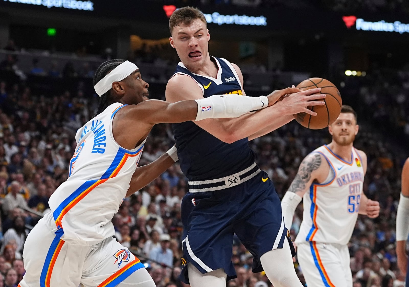 Oklahoma City Thunder guard Shai Gilgeous-Alexander, left, blocks Denver Nuggets guard Christian Braun, front right, on the way to the basket in the first half of Game 4 in the Western Conference semifinals of the NBA basketball playoffs Sunday, May 11, 2025, in Denver. (AP Photo/David Zalubowski)