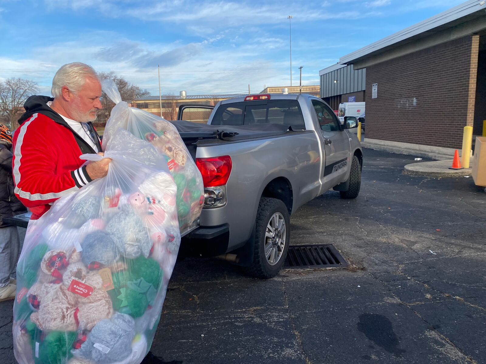 Joel Engelmeir of Planes Moving and Storage, which sponsors the annual gift drive, helps move presents into a store house. People came to a parking lot on Saturday, Dec. 16, 20223 off North Keowee Street in Dayton to donate stuffed animals, toys and more to Dayton Children's Hospital for the holidays. Eileen McClory / staff