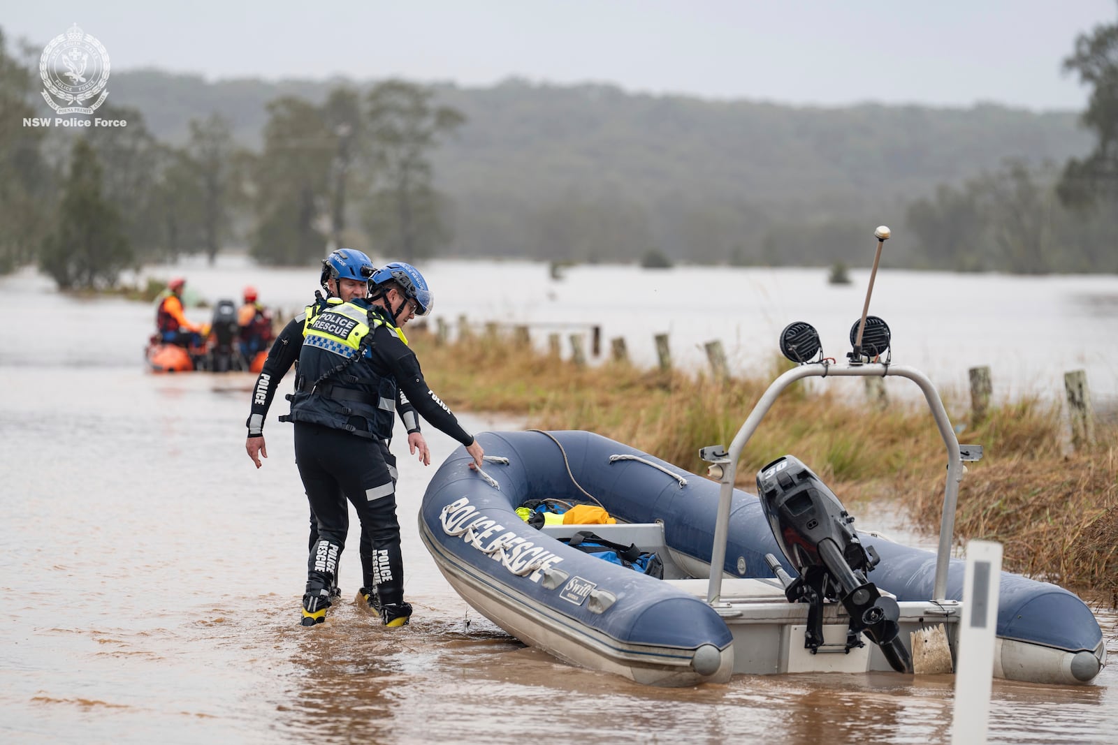 In this photo provided by the New South Wales Police, emergency workers wade through floodwaters as they prepare inflatable boats to effect rescues near Taree, Australia, Thursday, May 22, 2025. (NSW Police via AP)