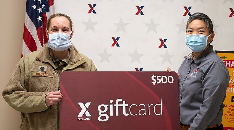 Keola Chan, Army and Air Force Exchange Service general manager for Wright-Patterson Air Force Base, presents Lt. Col. Stefani Diedrich, 88th Surgical Operations Squadron anesthesiologist, with a ceremonial $500 gift card Jan. 27 for winning the Holiday Pet Costume Contest. Chan said Diedrich was just one of several local winners in recent AAFES contests and sweepstakes. U.S. AIR FORCE PHOTO/R.J. ORIEZ