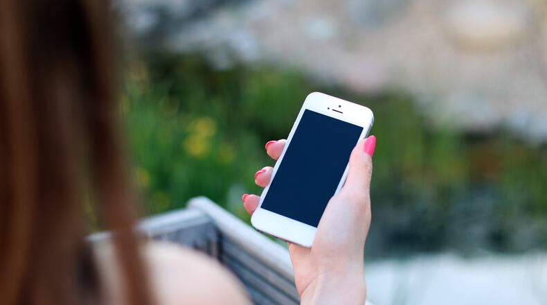 Stock photo of woman holding phone, via pexels.com.