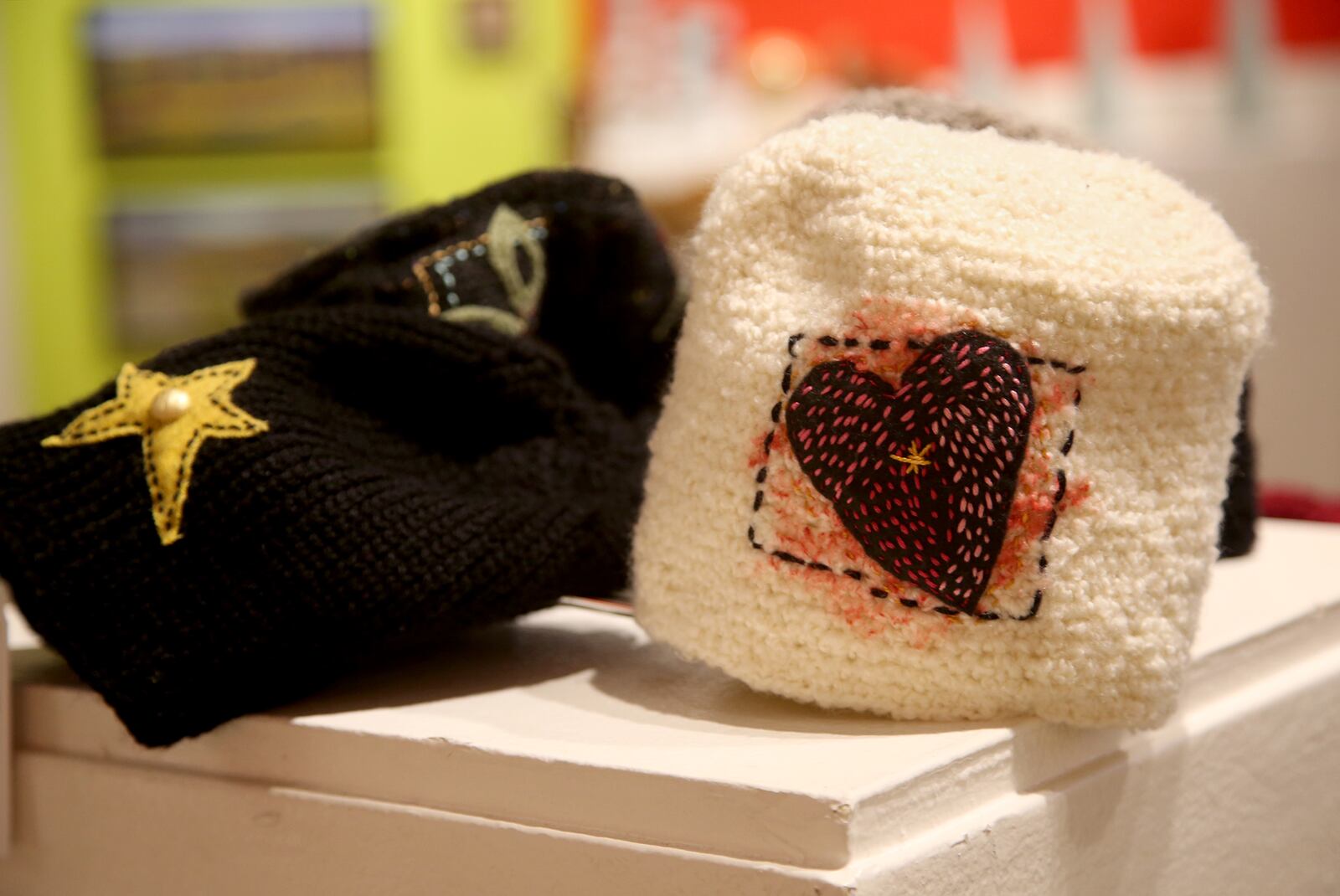 Hats, created by Storylines, are crocheted accessories inspired by poetry, literature and music.  A saying attributed to Buddha, “They way is not in the sky. They way is in the heart,”  was the inspiration for one of the pieces, a white hat hand embroidered with a heart. The hats cost $45. LISA POWELL / STAFF
