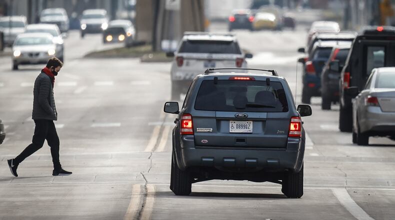 Pedestrians make their way across Main Street in Downtown Dayton Wednesday morning Jan. 19, 2022. 
JIM NOELKER/STAFF
